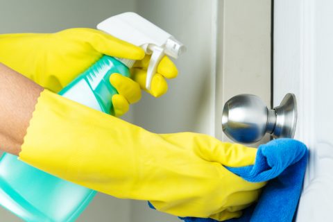 Cleaning door knob with alcohol spray for Covid-19 Coronavirus prevention